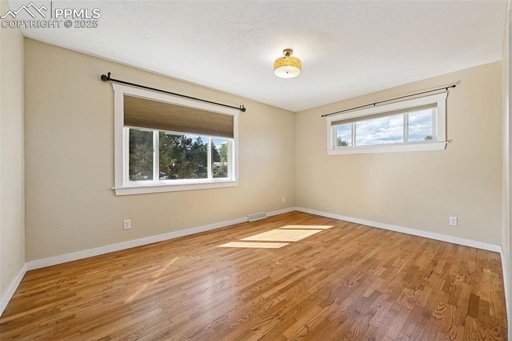 1305 Sunset Road Colorado Springs, CO 80909 - Photo 15 of 50 a view of an empty room with window and wooden floor