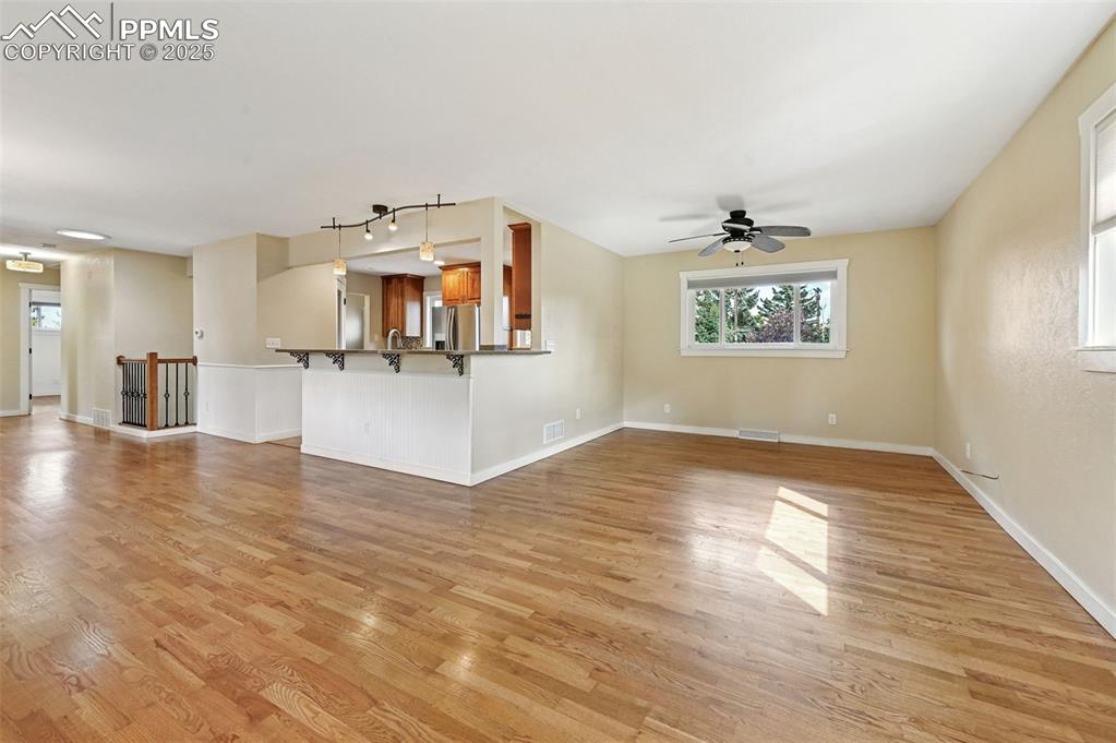 1305 Sunset Road Colorado Springs, CO 80909 - Photo 7 of 50 an empty room with wooden floor and kitchen view