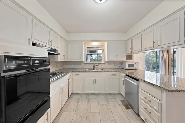 a kitchen with granite countertop cabinets stainless steel appliances a sink and a window