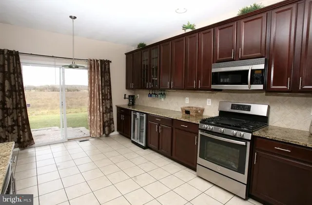 a kitchen with granite countertop a stove a microwave a sink and cabinets
