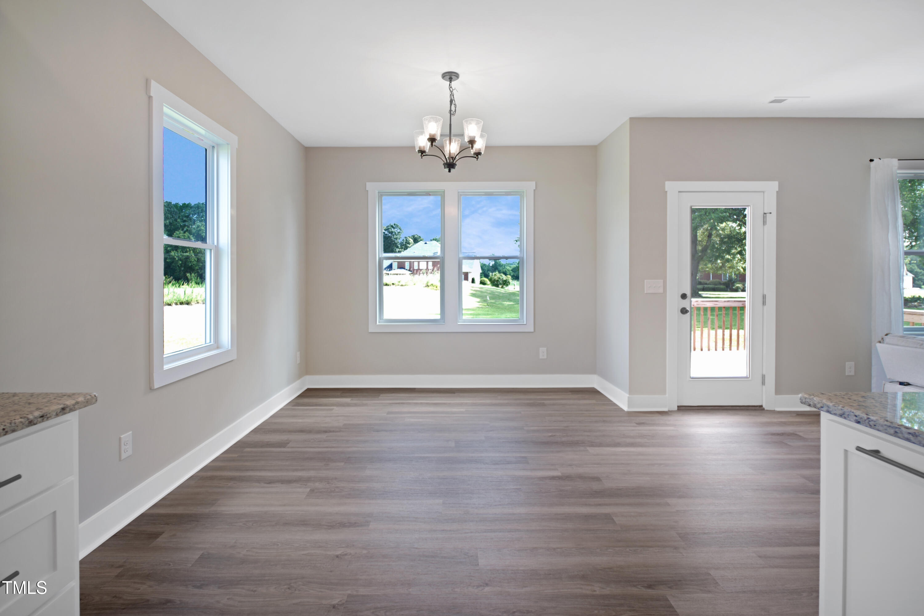 101 Sand Trap Lane Clinton, NC 28328 - Photo 27 of 49 an empty room with wooden floor chandelier and windows