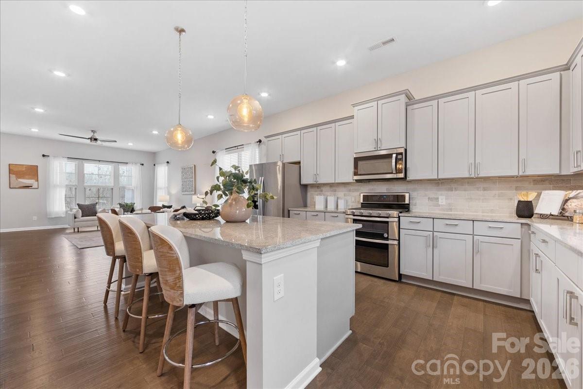 9205 Bluefield Street Charlotte, NC 28273 - Photo 14 of 48 a kitchen with stainless steel appliances granite countertop a stove top oven a sink a refrigerator with white cabinets and wooden floor