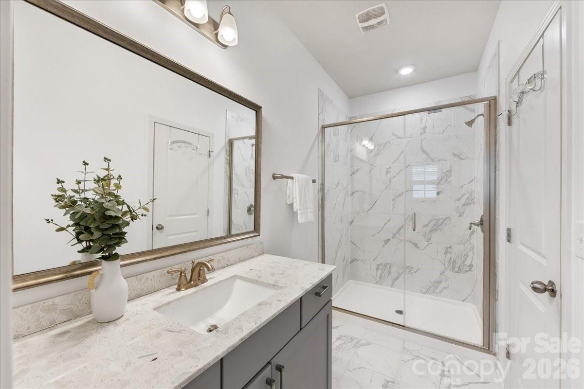 9205 Bluefield Street Charlotte, NC 28273 - Photo 37 of 48 a bathroom with a granite countertop sink a mirror a bathtub and shower