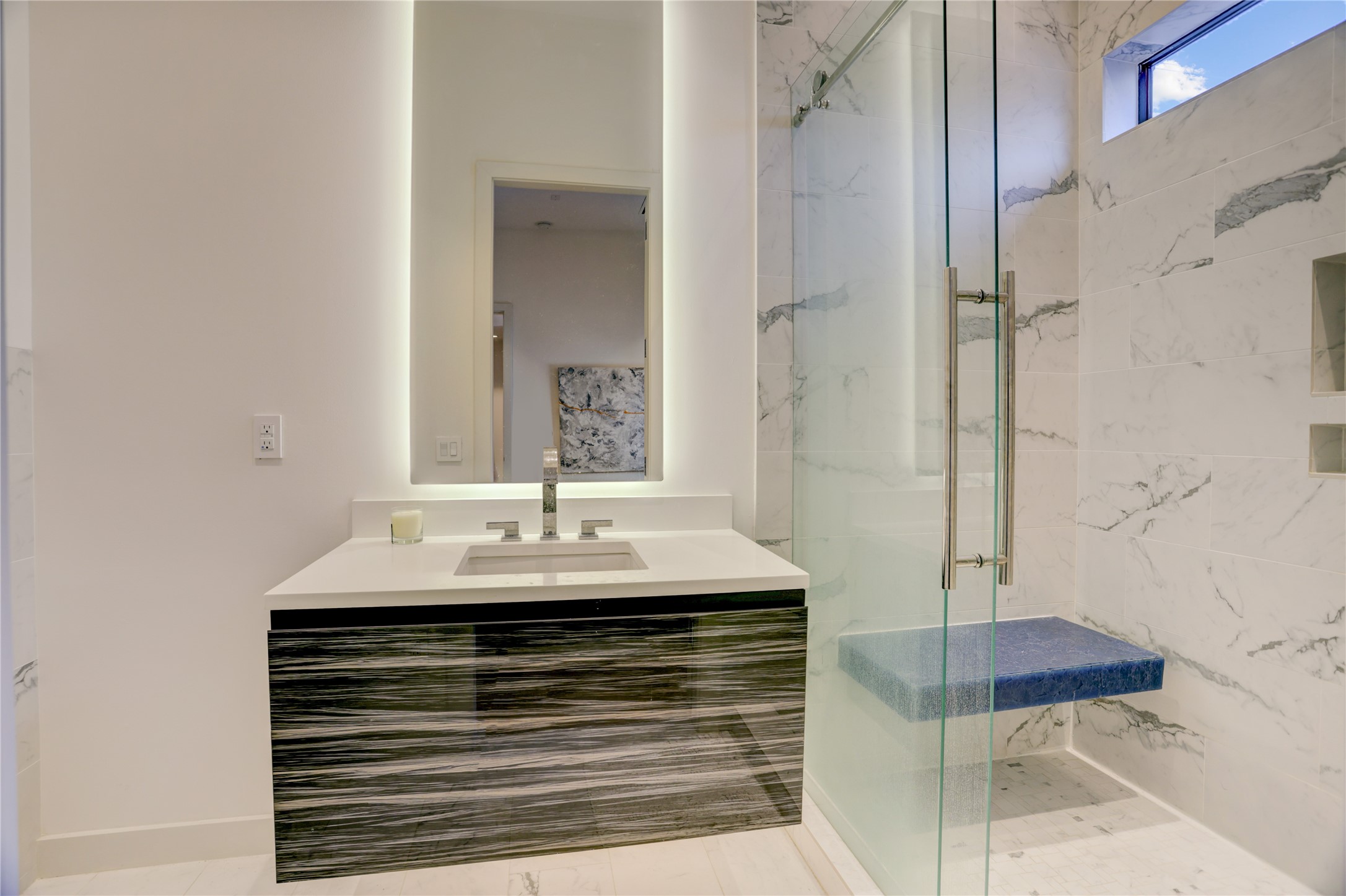 1807 Indiana Street Houston, TX 77006 - Photo 22 of 35 En-Suite Bath: Modern attached bathroom featuring a linear-grain floating vanity, a vertical backlit LED mirror, and a walk-in tile shower with a frameless glass door and a built-in shower bench.