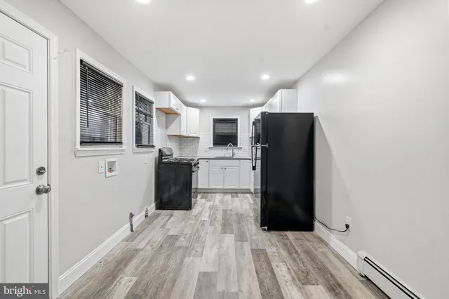 a view of a kitchen with refrigerator and wooden floor