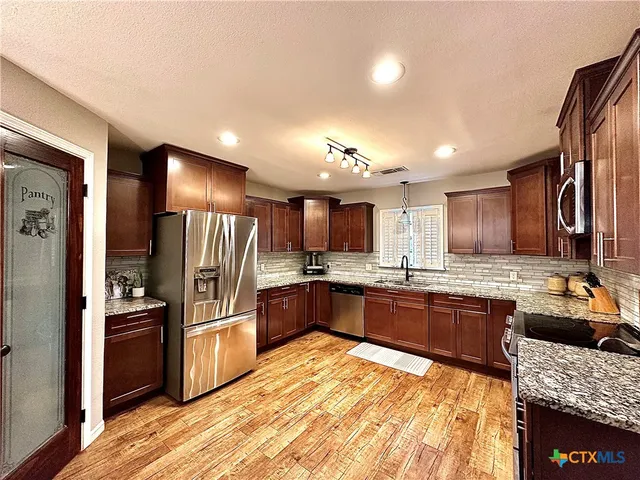 a large kitchen with kitchen island granite countertop a large counter top stainless steel appliances and cabinets