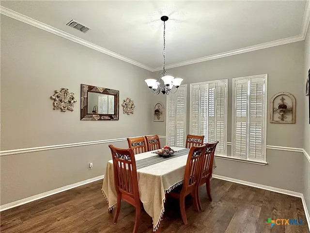 a dining room with furniture a chandelier and wooden floor