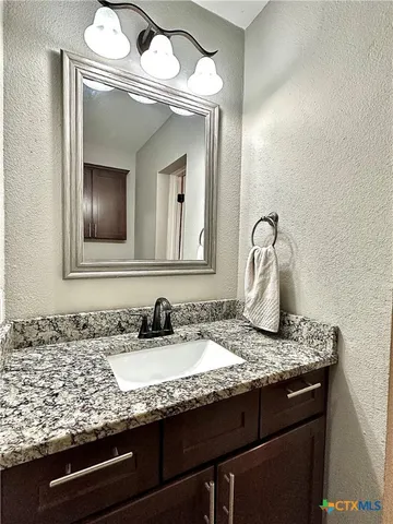 a bathroom with a granite countertop sink and a mirror