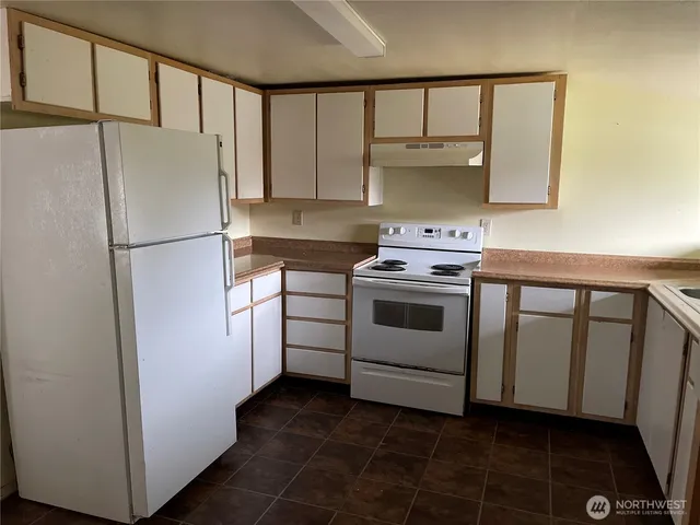 a white refrigerator freezer and a stove sitting inside of a kitchen