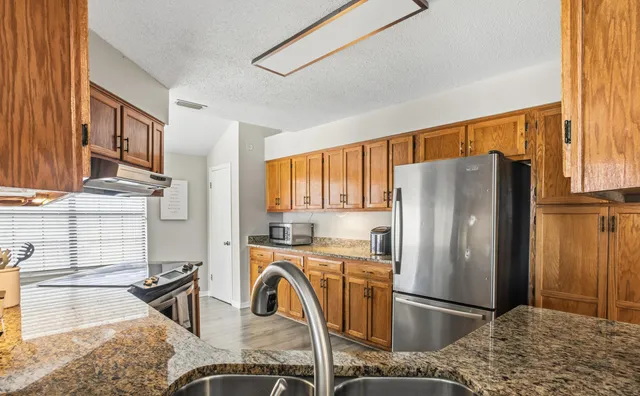 a kitchen with stainless steel appliances granite countertop a refrigerator a stove and a sink