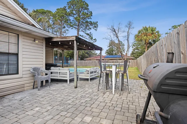 a view of a patio with dining table and chairs with a barbeque grill and plants