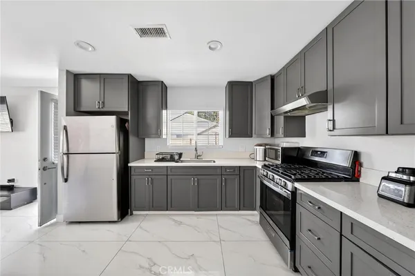 a kitchen with granite countertop a refrigerator sink stove and cabinets