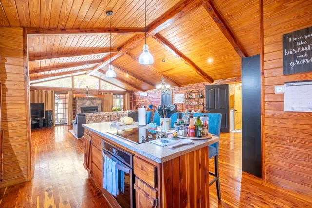 a view of kitchen island with stainless steel appliances granite countertop a sink and wooden floor