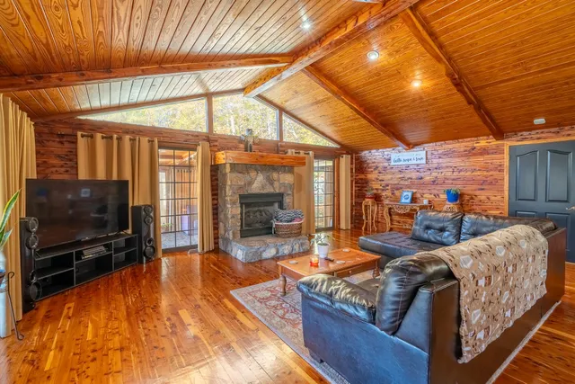 a living room with furniture a flat screen tv and floor to ceiling window