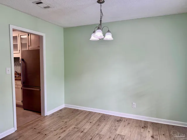 a view of empty room with wooden floor and kitchen
