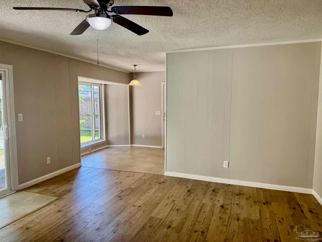 an empty room with wooden floor fan and windows