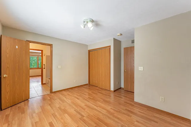 a view of an empty room with wooden floor and closet