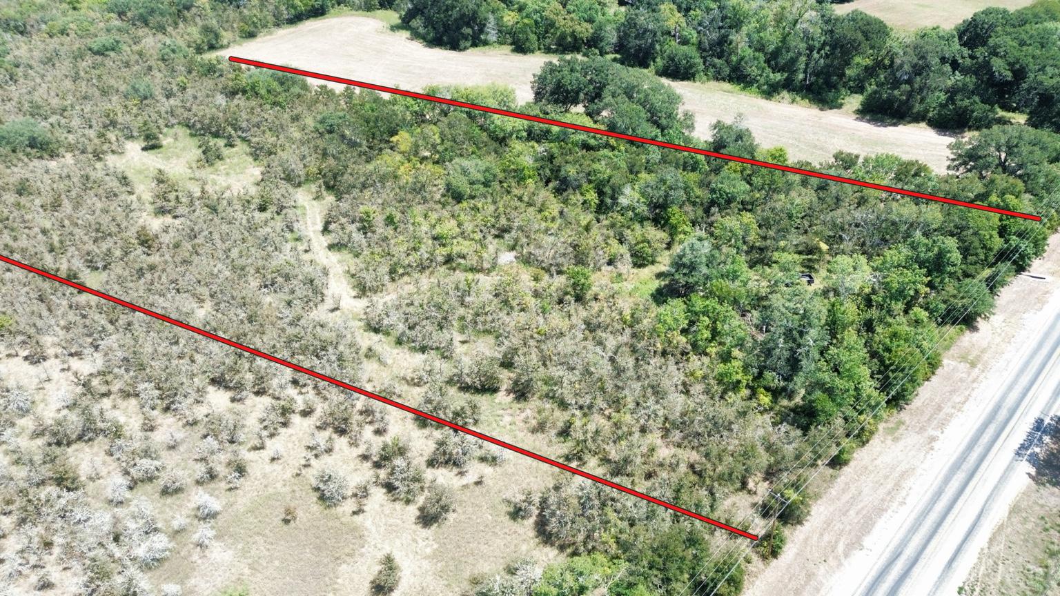 Fm Fm 141st Dime Box, TX 77853 - Photo 2 of 5 Lush trees and open meadows meet along a paved two-lane road in this aerial view.