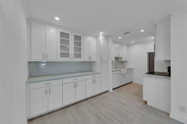 a kitchen with white cabinets and sink