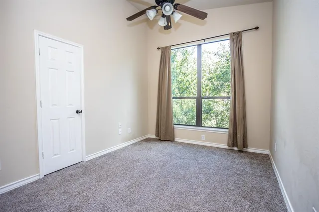 an empty room with a chandelier fan and windows