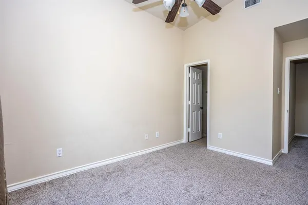 an empty room with a ceiling fan and carpet