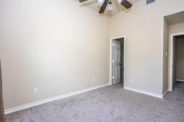 an empty room with a ceiling fan and carpet