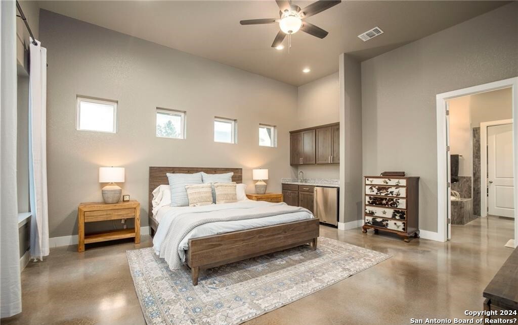 345 Laguna Road Bandera, TX 78003 - Photo 11 of 35 a spacious bedroom with a bed and a chandelier
