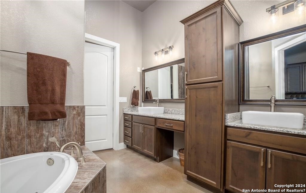 345 Laguna Road Bandera, TX 78003 - Photo 14 of 35 a bathroom with a granite countertop bathtub sink and mirror