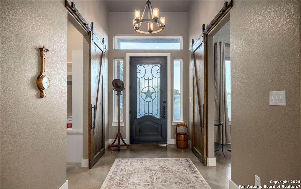345 Laguna Road Bandera, TX 78003 - Photo 10 of 35 a hallway with windows and a chandelier