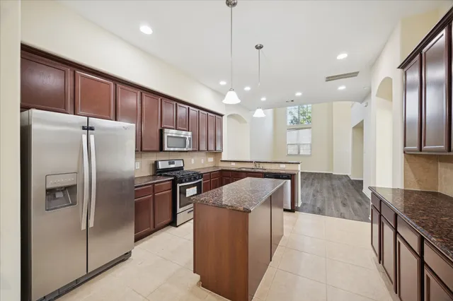 a kitchen with stainless steel appliances granite countertop a refrigerator a sink a stove and a wooden cabinets