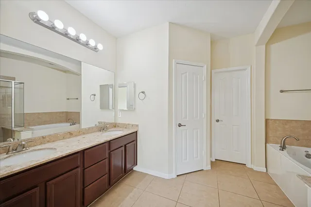 a spacious bathroom with a granite countertop sink a mirror and a bathtub