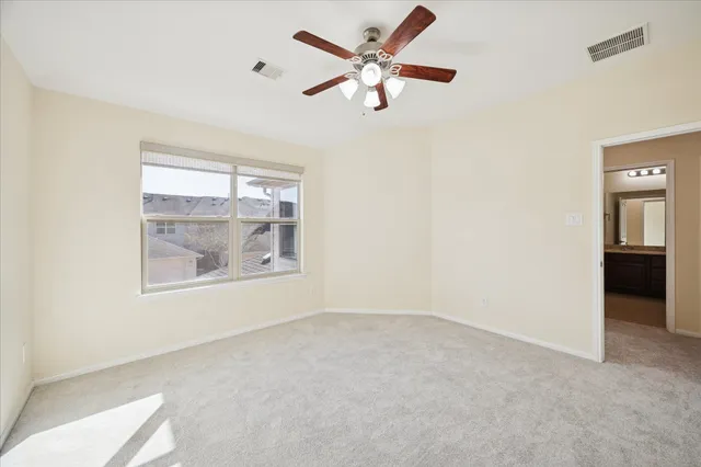 an empty room with a window and a ceiling fan