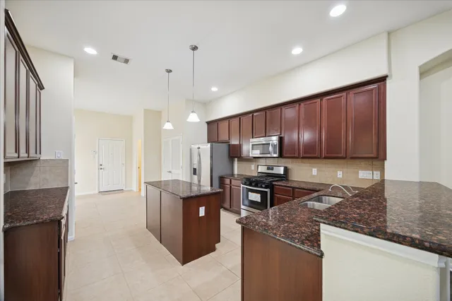 a kitchen with kitchen island granite countertop a sink counter top space appliances and cabinets