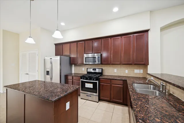 a kitchen with stainless steel appliances granite countertop a stove a refrigerator a sink a oven with a dining table and chairs