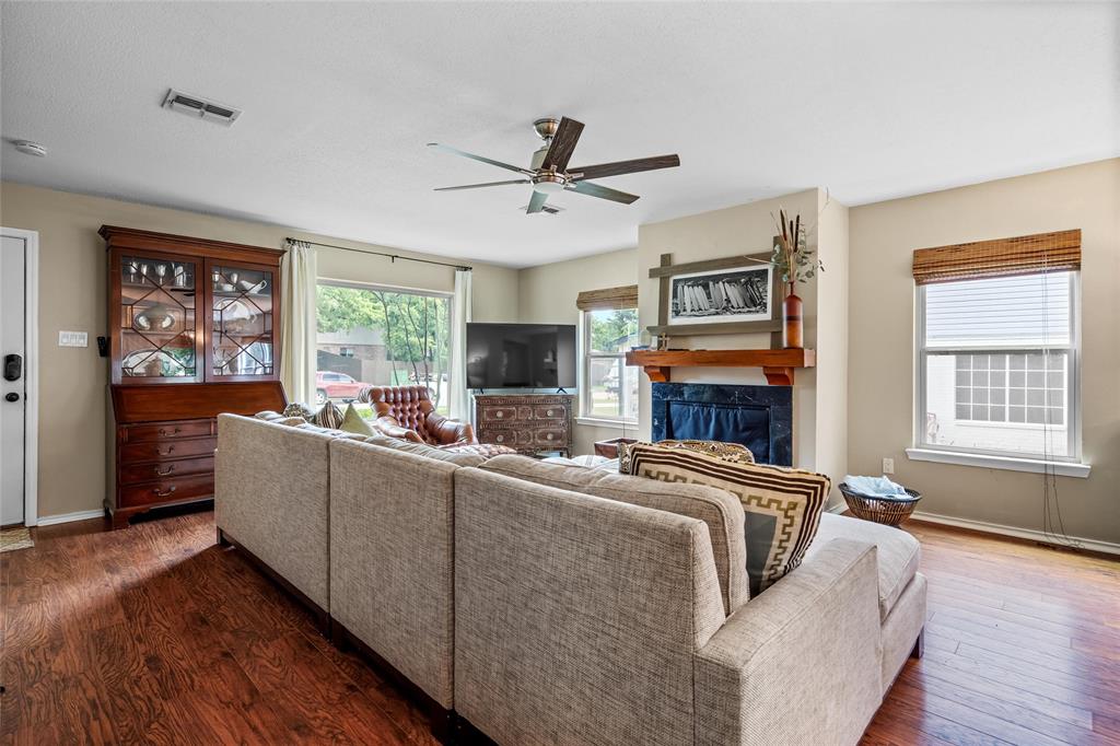 1901 Yellowstone Lane Corinth, TX 76210 - Photo 11 of 32 Living area featuring plenty of natural light, dark wood-style floors, a ceiling fan, and a glass covered fireplace