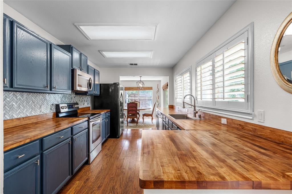 1901 Yellowstone Lane Corinth, TX 76210 - Photo 2 of 32 Kitchen with wooden counters, blue cabinets, stainless steel appliances, tasteful backsplash, and hanging light fixtures