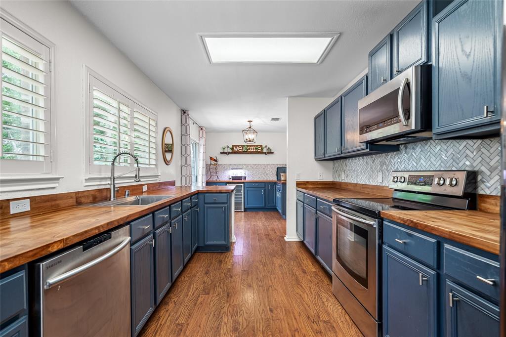 1901 Yellowstone Lane Corinth, TX 76210 - Photo 5 of 32 Kitchen with wooden counters, blue cabinetry, stainless steel appliances, tasteful backsplash, and dark wood finished floors