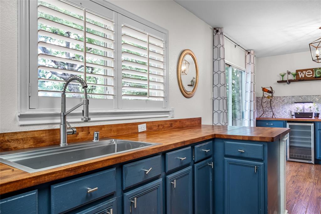 1901 Yellowstone Lane Corinth, TX 76210 - Photo 6 of 32 Kitchen featuring blue cabinetry, butcher block countertops, beverage cooler, tasteful backsplash, and open shelves