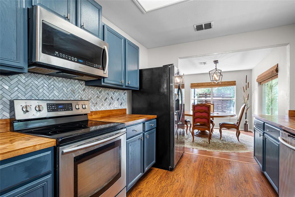 1901 Yellowstone Lane Corinth, TX 76210 - Photo 7 of 32 Kitchen featuring butcher block counters, stainless steel appliances, blue cabinets, and wood finished floors