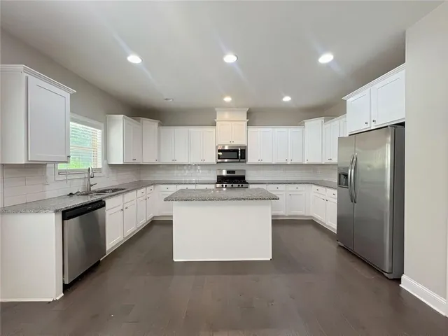 a kitchen with stainless steel appliances granite countertop white cabinets and refrigerator