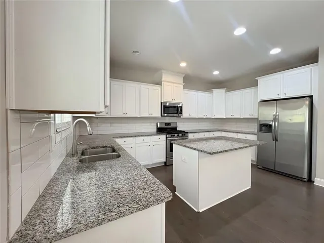 a kitchen with granite countertop white cabinets and white appliances