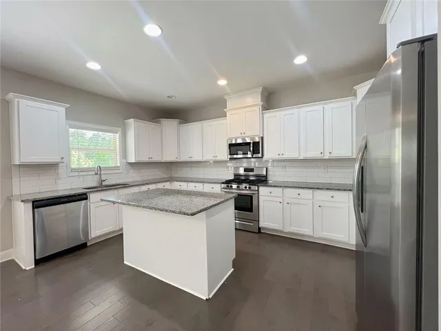 a kitchen with granite countertop kitchen island a sink appliances and a counter top space