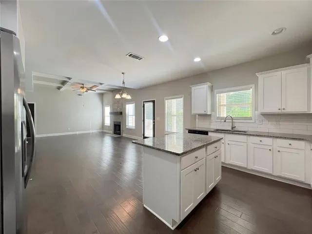 a kitchen that has a lot of cabinets and wooden floor