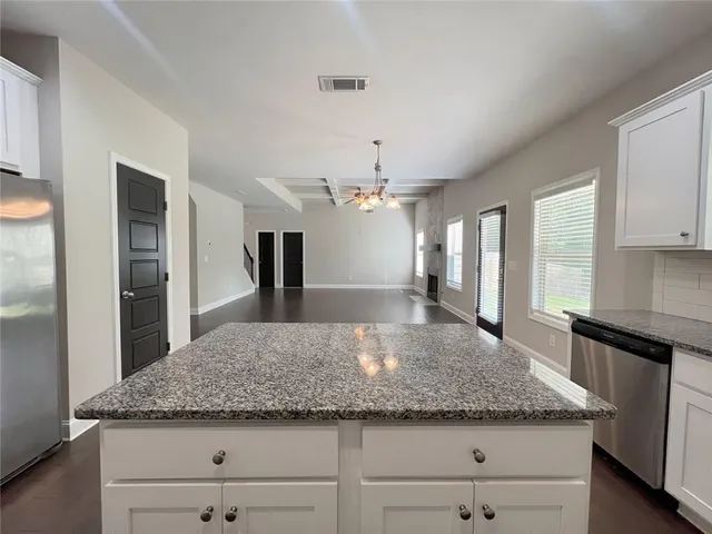a kitchen with granite countertop white cabinets stainless steel appliances and a counter space