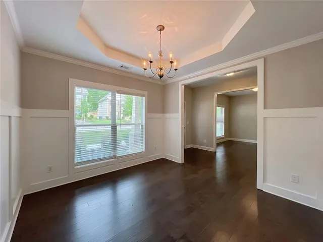 an empty room with wooden floor and windows with curtains