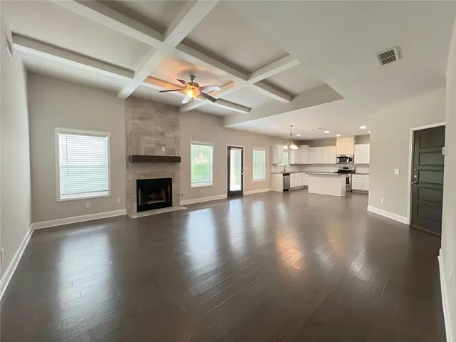 a view of an empty room with a fireplace and a ceiling fan