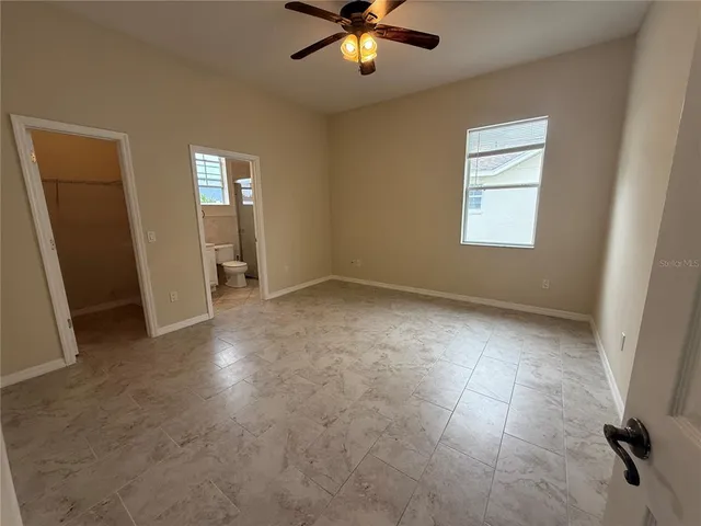 an empty room with windows and fan