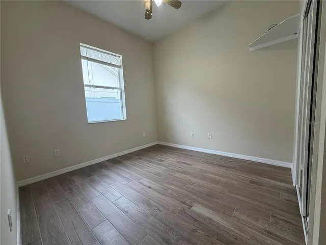 an empty room with wooden floor cabinet and windows