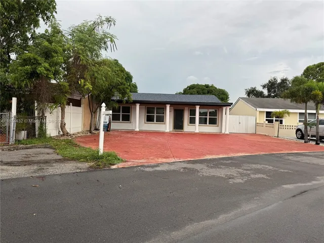 a front view of a house with a yard and potted plants