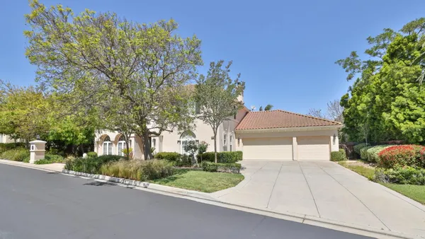 a front view of a house with a yard and trees